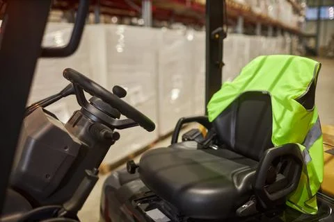 Forklift interior with reflective jacket on empty drivers seat Stock Photos