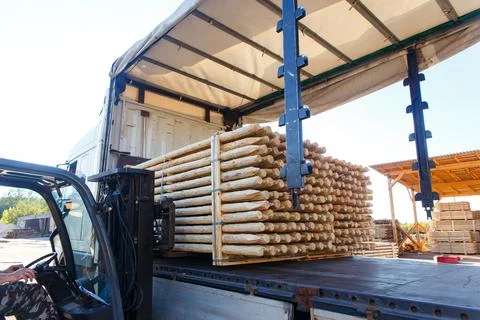 Forklift loading a bundle of pointed wooden stakes onto a truck trailer Fotos de archivo