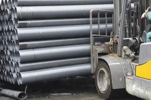 Forklift loading polypropylene pipes in warehouse Stock Photos