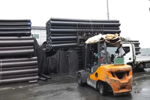 Forklift loading polypropylene pipes in warehouse Stock Photos