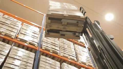 Forklift in a logistics warehouse lifts pallets onto shelves. Overview of pallet Stock Footage