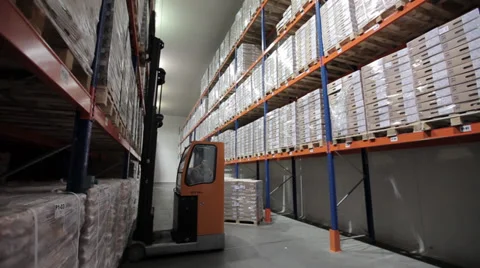 Forklift in a modern logistics warehouse distributes goods in boxes on shelves o Stock Footage 36840778