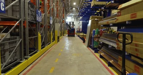 Forklift moves between rows with goods lying in a warehouse Stock Footage 126953510
