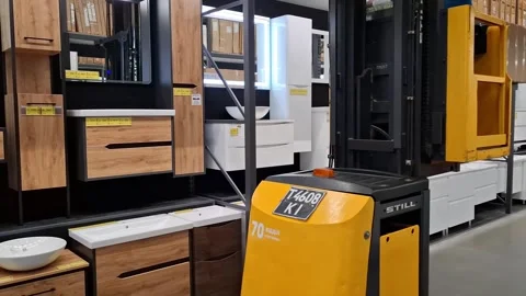 Forklift moves between rows of goods in a construction hypermarket Stock Footage 309646523