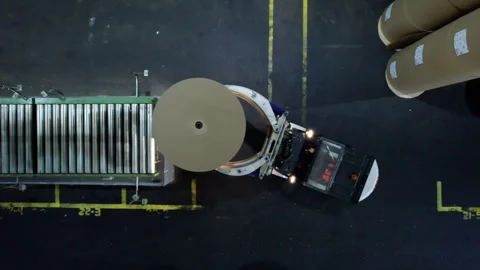 Forklift operator steers vehicle to remove paper roll from conveyor belt Stock Footage 290517287