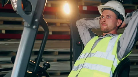 Forklift Operator Taking a Break While Sitting in Warehouse Vídeos de archivo 345013254