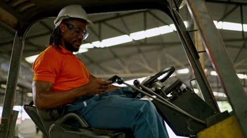 Forklift operator using smartphone inside warehouse cab during material han.. Stock Footage 332503093