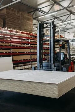 A forklift skillfully lifts a massive stack of sheets in a large, well-organi Stock Photos