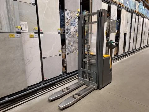 Forklift stands between rows of goods in a construction hypermarket Photos