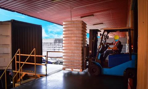 Forklift stuffing-unstuffing cargo to container on warehouse leveler dock. 写真素材
