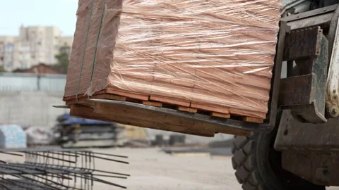 Forklift transporting pallet of bricks wrapped in plastic at construction site Vídeos de archivo 348537543