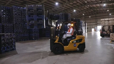 Forklift truck driver loading gallon water bottle stack onto industrial Stock Footage 141102916