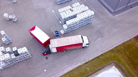 Forklift trucks move between large shelves at outside warehouse and load pall Stock Footage 88127288