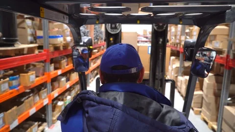 Forklift trucks move between large metal shelves at modern warehouse with Stock Footage 102748808