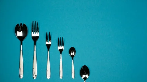 Forks and spoons from small to large in one row on blue background. Stock Footage 87786239