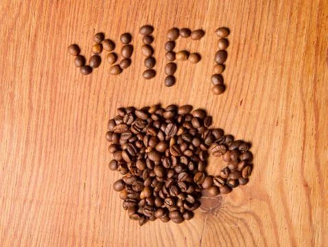 Form a coffee cup made of coffee beans on the wood background Stock Photos
