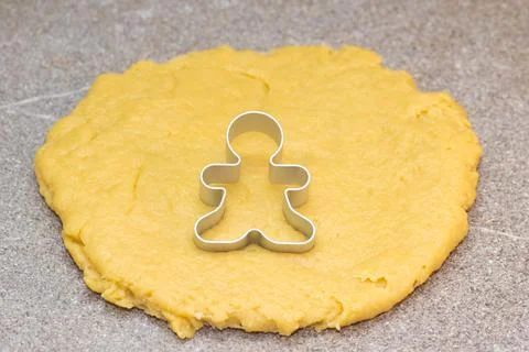 Form for cutting gingerbread men on raw rolled dough on a gray background. Th Stock Photos