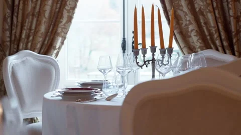 Formal dining table set with white chairs and a golden candelabra Stock Footage 332310772