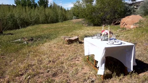 Formal dining table set in wilderness outdoor setting wind blowing Stock-Footage 75024794