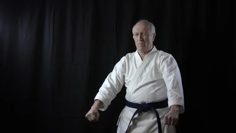 Formal exercises karate are trained by an old male athlete Stock Footage 127942865
