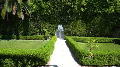 Formal garden path with trimmed hedges and white gate Stock Footage 345687230