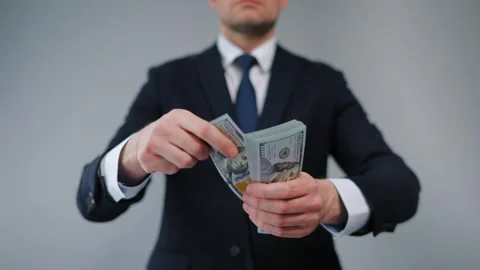 Formally dressed man carelessly throws US Dollar bills towards the camera Stock Footage 290436498