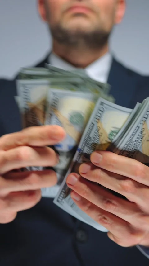 Formally dressed man is counting US Dollar bills, close-up. Stockbeeldmateriaal 343572173