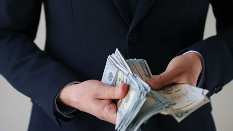 Formally dressed man holding US dollar and polish zloty banknotes. Concept of Stock Footage 176560383