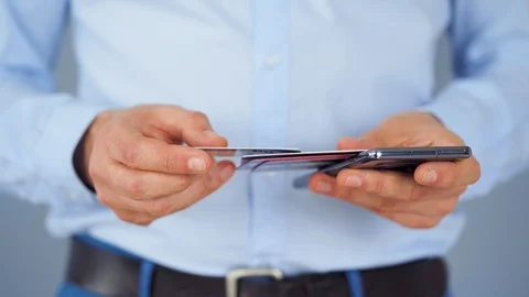 Formally dressed man selects a credit card from several and enters it number Stock Footage 121419795