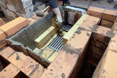 Formation of a fireclay core for a solid fuel furnace. A bricklayer is laying Stock Photos
