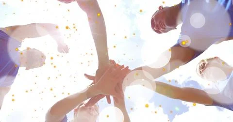 Forming six teammates stacking hands overhead outdoors, wearing athletic tops Stock Photos