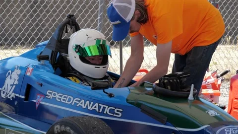 Formula One  driver in the car. Crew member fixing driver gear. 库存影片 157806987