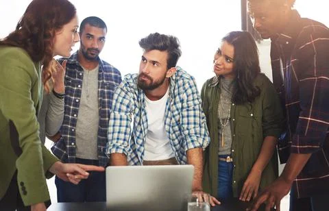 Formulating a plan of action. a group of colleagues working on a laptop in an Stock Photos