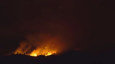 A forrest fire burning the top of a mountain at night with high flames glowin Stock Footage 132934813