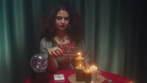 Fortune Teller Blowing out Fire on Burning Stick, Sitting at Table with Candles Stock Footage 253180811