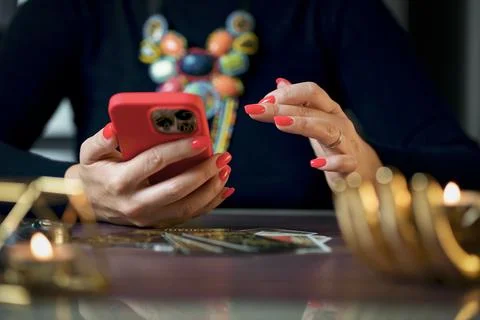 A fortune teller does online fortune telling on photos from a smartphone. Stock Photos
