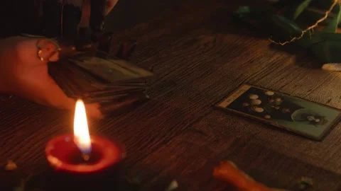 Fortune teller hands arranging tarot cards on a dimly lit wooden table, engaging Stock Footage 318870161