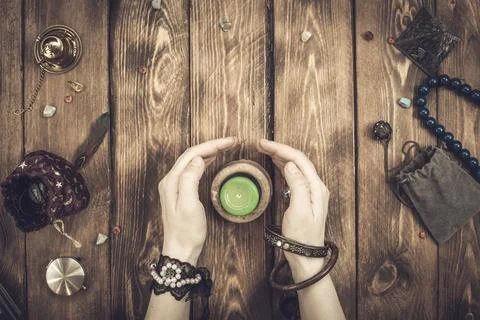 A fortune teller or an oracle with objects for divination holds an extingui.. Stock Photos