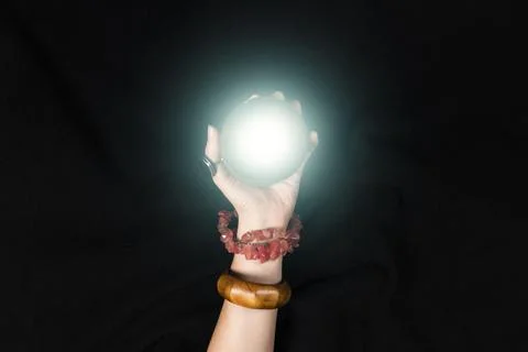 Fortune teller or witch hand and a glowing magic ball isolated on black Stock Photos