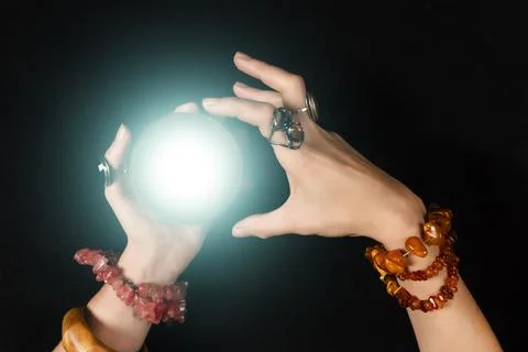 Fortune teller or witch hands and a glowing magic ball isolated on black Stock Photos