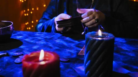 A fortune teller at a table in candlelight reads the future from tarot cards on Stock Footage 232526286