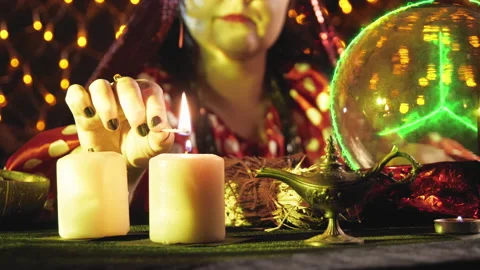 A fortune teller in yellow light lights candles before the start of the session Stock Footage 168379722