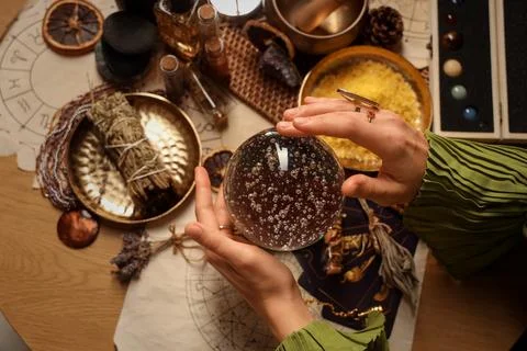 Fortune teller's hands with crystal ball reading future on table, top view Stock Photos