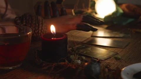Fortune teller's hands laying out tarot cards on a wooden table, performing a Stock Footage 318869636