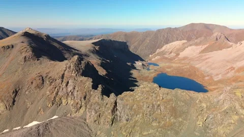 Forward aerial flight across rocky alpine pass to lakes Stock Footage 336333340