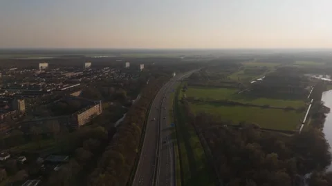 Forward aerial flyover above highway traffic near Dutch town at sunset Stock Footage 335831977