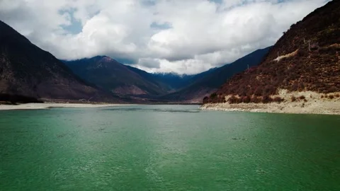 Forward aerial over green river water between Tibetan mountains Video stock 345880768