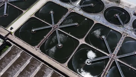 Forward birds eye drone shot above circular and square clarifier tanks Stock Footage 338102930