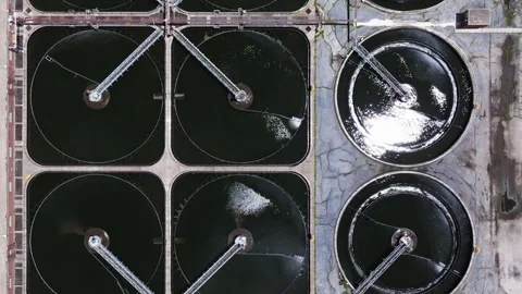 Forward birds eye drone shot above square and circular clarifier tanks with Stock Footage 338103017