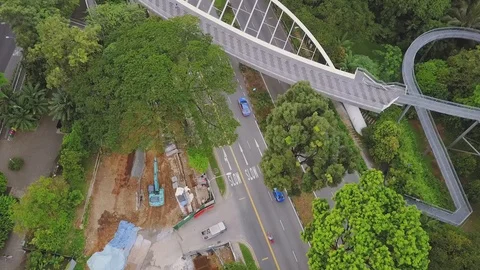 Forward bird's eye view of a uniquely shaped pedestrian bridge above a busy road Stock Footage 108801842